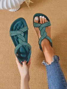 Detail view of teal flat sandals with sparkling rhinestone-embellished wavy straps.