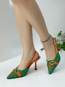 Close-up view of green woven slingback heels with orange floral embroidery and gold buckle.