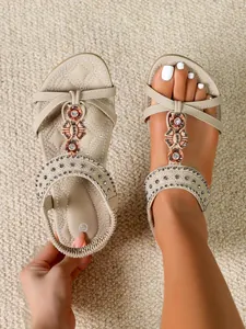 Close-up detail of bohemian flat sandals with rhinestones and flower beads on a foot.