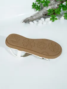 Detailed view of brown anti-slip floral patterned sole on white flat sandals