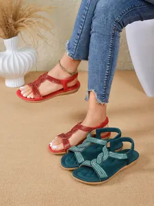 Close-up of bohemian flat sandals with sparkling rhinestone straps in red and teal green.