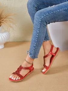Close-up detail of women's red ethnic sandals with intricate black rhinestone patterns.
