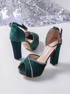 Detailed macro view showing the texture of dark green velvet platform heels with rhinestone trim