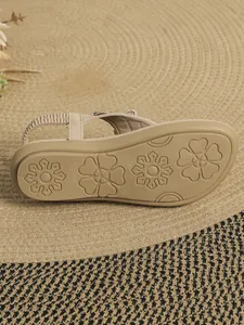 Close-up view of non-slip floral patterned sole on these beige flat thong sandals