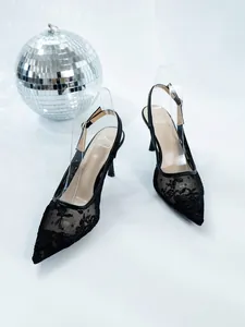Close-up of black lace pointed-toe high heels with floral embroidery and slingback strap.