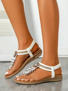 Detailed macro shot of white bohemian flat sandals featuring colorful beads and tassel accents