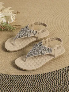 Detailed view of beige flat thong sandals with intricate rhinestone floral accents