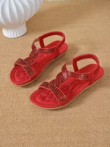 Detail view of red flat sandals featuring sparkling rhinestones and ethnic style straps