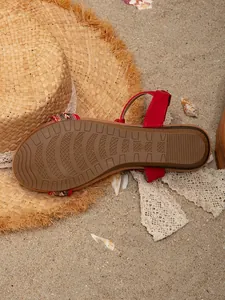 Detailed macro view of the non-slip sole of a bohemian beaded sandal on beach sand