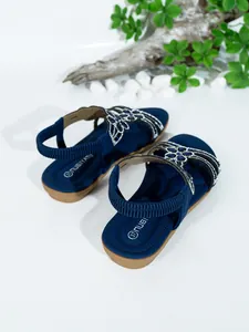 Close-up of navy blue bohemian flat sandals with sparkling rhinestone floral details.