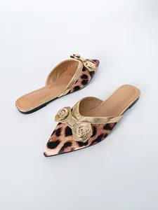 Detail van puntige mules met luipaardprint en een goudkleurige metalen strik met strass.