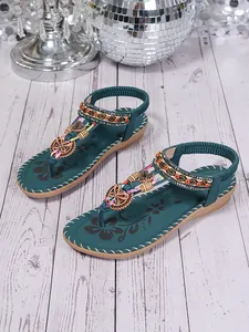 Detail of Bohemian teal flat sandals featuring ethnic beadwork and butterfly charms.