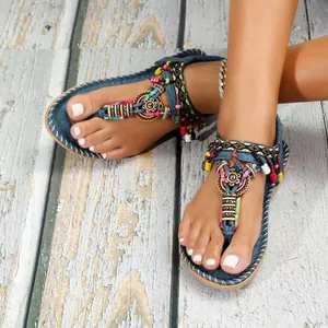 Λεπτομέρεια από φλατ σανδάλια Bohemian με πολύχρωμα μενταγιόν και σχέδιο T-strap