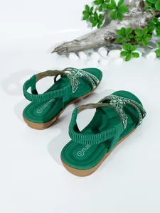 Close-up detail of green Bohemian flat sandals with sparkling rhinestone floral patterns