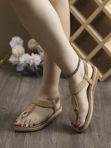 Detalle de sandalias planas bohemias color canela puestas en los pies de una modelo