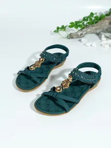 Detalle de sandalias planas bohemias verde azulado con adornos de cuentas florales