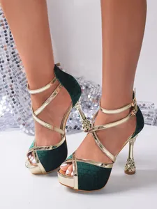 Close-up view of elegant green velvet cross strap sandals with gold stiletto heels