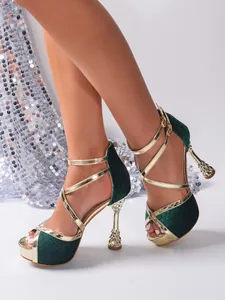 Detail view of green velvet high heels with gold cross straps and decorative goblet heels.