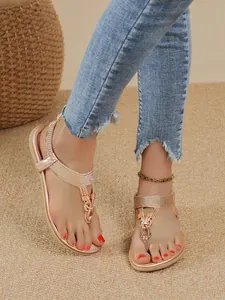 Detail of Bohemian rose gold flat sandals with braided straps and decorative buckle