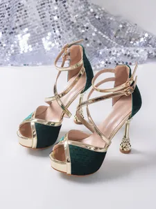 Detailed view of dark green velvet high heels with gold metallic crossover straps.