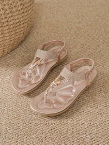 Close-up of bohemian rose gold flat sandals with rhinestone T-strap details and elastic strap
