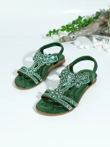 Detailed view of green Bohemian flat sandals featuring sparkling rhinestone floral patterns.