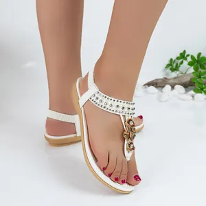 White bohemian flat sandals with sparkling rhinestones and floral T-strap detail for women.