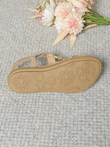Detailansicht von flachen Boho-Sandalen mit handgefertigten Holzperlen und funkelnden Strass