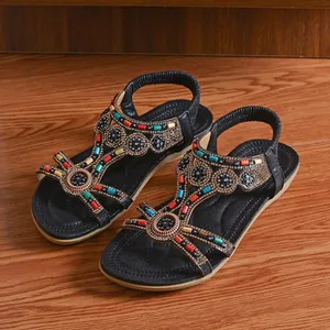 Ethnic style women's flat sandals with rhinestones and colorful beads on wooden floor