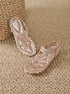 Elegant detail view of rose gold bohemian flat sandals with T-strap design on a mat