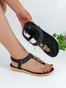 Detail view of black Bohemian flat sandals with sparkling rhinestones and floral decor.