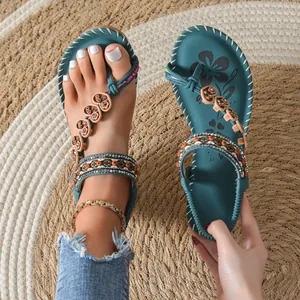 Close-up of Bohemian teal sandals with colorful beads and heart charms on a woven mat.