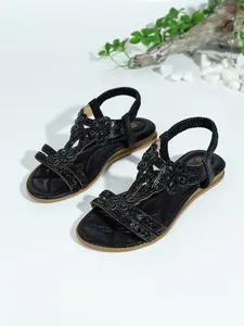 Elegant black flat sandals for women featuring sparkling floral rhinestone detailing.