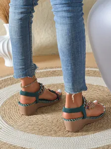 Close-up detail of bohemian teal wedge sandals with colorful beads and heart charm