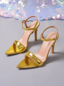 Detail van de elegante gouden 9cm naaldhakken met een puntige neus en enkelbandje
