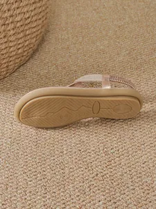 Detailed view of the non-slip wavy patterned sole of a rose gold bohemian flat sandal