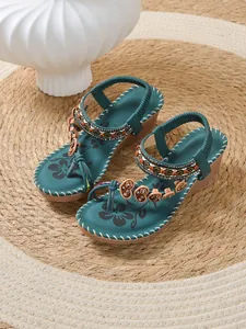 Detailed view of teal bohemian wedge sandals featuring intricate beadwork and heart charms