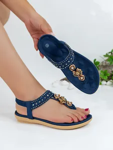 Detail view of navy blue Bohemian flat sandals with sparkling rhinestones and floral accents.