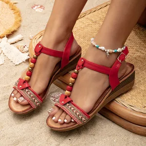 Women's red Bohemian wedge sandals with beaded T-straps and embroidered details on sand