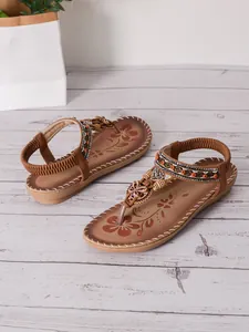 Detail shot of Bohemian style flat sandals with beaded straps and floral footbed pattern
