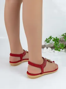 Detailed side view of red bohemian flat sandals featuring rhinestones and elastic straps