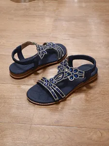 Detailed view of blue bohemian flat sandals with sparkling rhinestone floral patterns