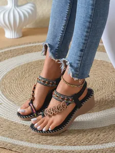 Detailed view of bohemian wedge sandals featuring beaded heart charms and colorful woven straps.