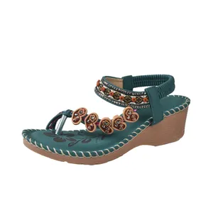 Stylish bohemian teal wedge sandals with colorful beads and heart charms on white background.