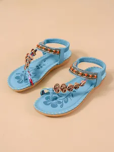 Detail shot of bohemian flat sandals with blue beads and heart-shaped ornaments