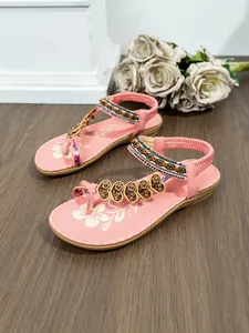 Stylish pink bohemian flat sandals with intricate beadwork and floral footbed pattern