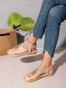 Primer plano de sandalias planas bohemias con cuentas y pedrería en una modelo