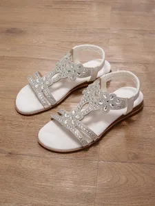 Elegant white bohemian flat sandals featuring sparkling rhinestone floral details