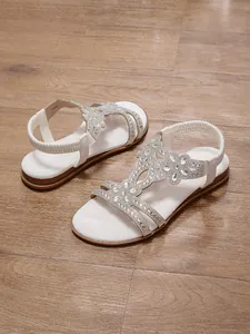 Detailed view of white bohemian flat sandals with sparkling rhinestone flower patterns