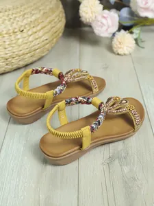 Primo piano di sandali bohémien con perline fatte a mano e cinturini intrecciati.